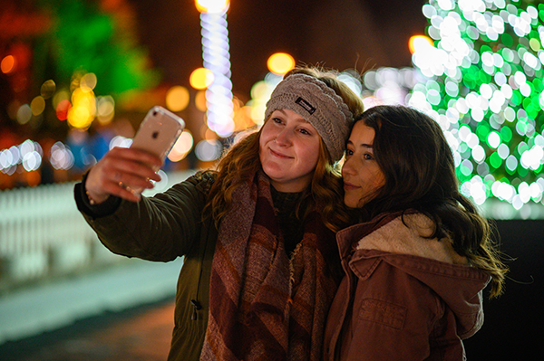 Girls snap a selfie in front of the tree